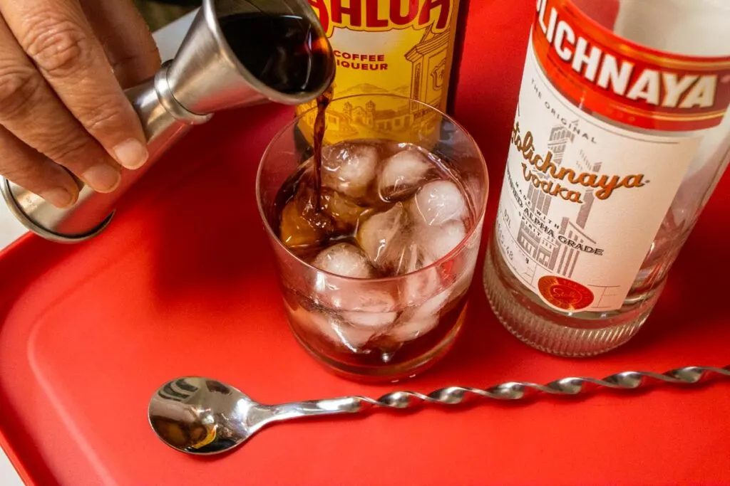 Pouring Kahlua into Black Russian Drink