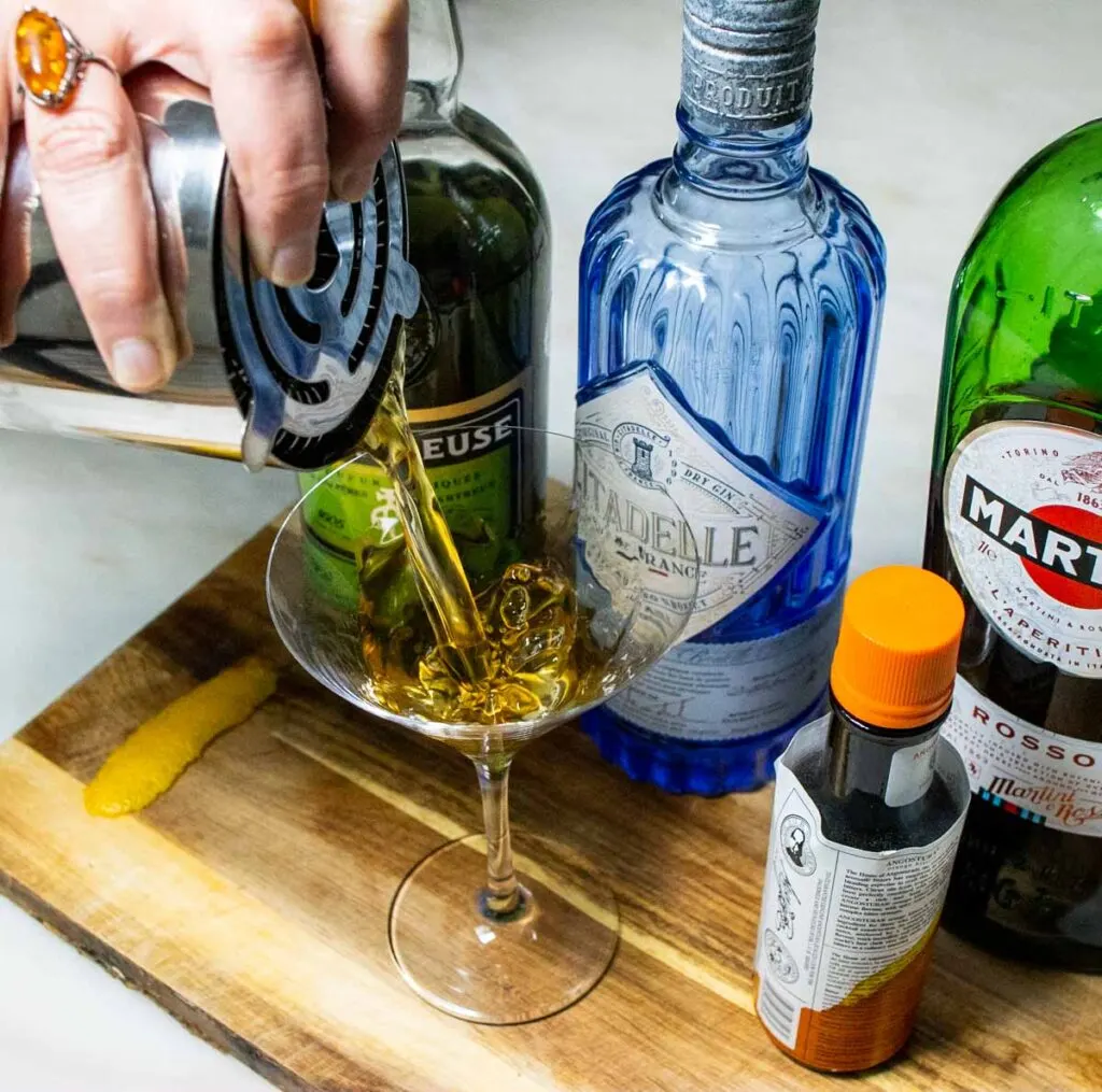 Straining Bijou Cocktail into Martini Glass
