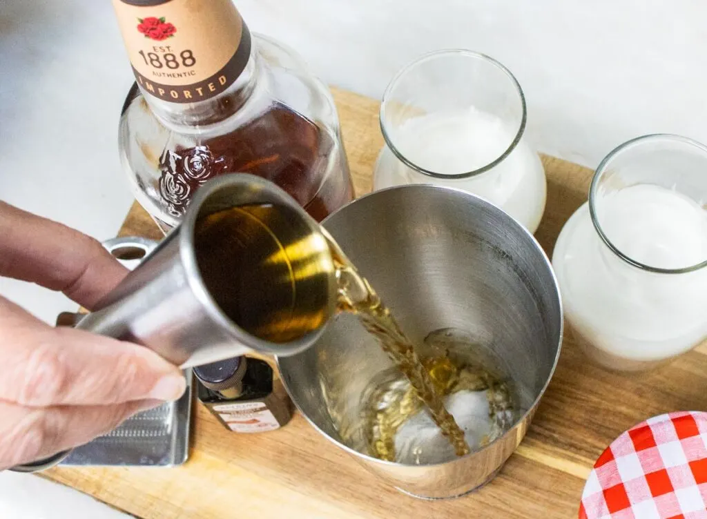 Pouring Bourbon for Bourbon Milk Punch Recipe