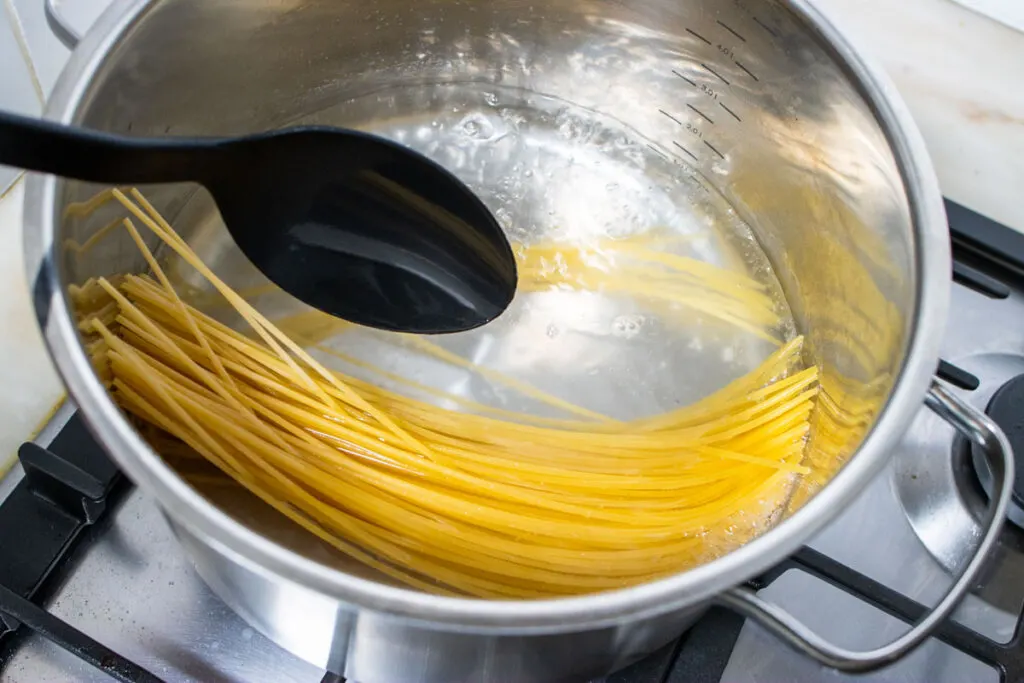 Pasta being fit into a sauce pan for cooking