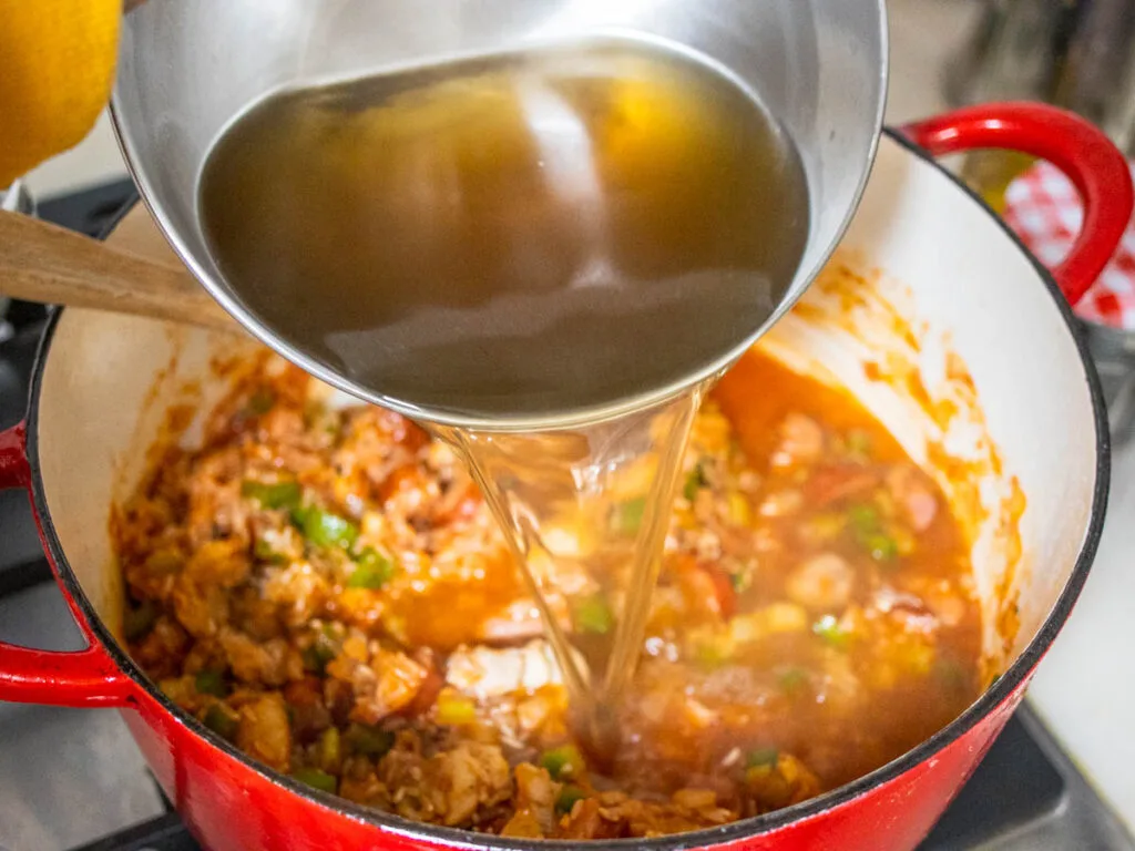 Pouring Chicken Broth in a Pot for Jambalaya