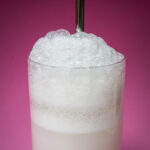 Ramos Gin Fizz Cocktail Up Close with Straw and Pink Background
