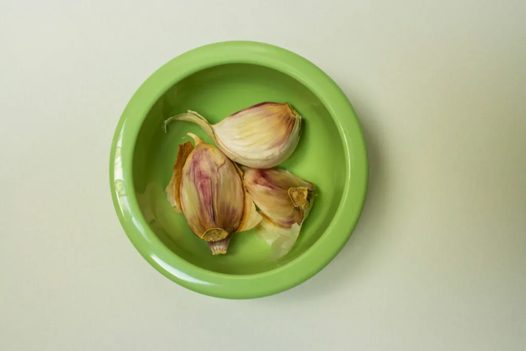 Whole unpeeled garlic cloves in a small bowl