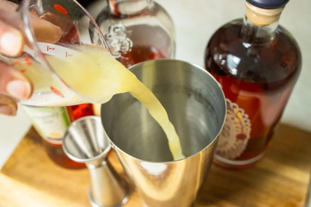 Pouring Lemon Juice for Paper Plane Cocktail Recipe