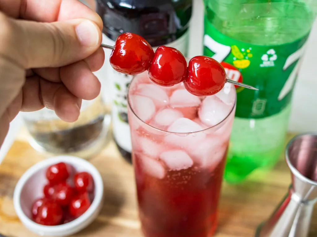Garnishing a Dirty Shirley Cocktail with Maraschino Cherries