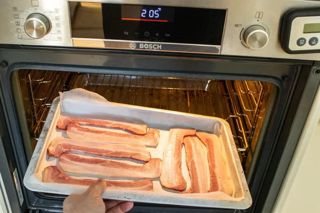 Placing raw bacon into an oven