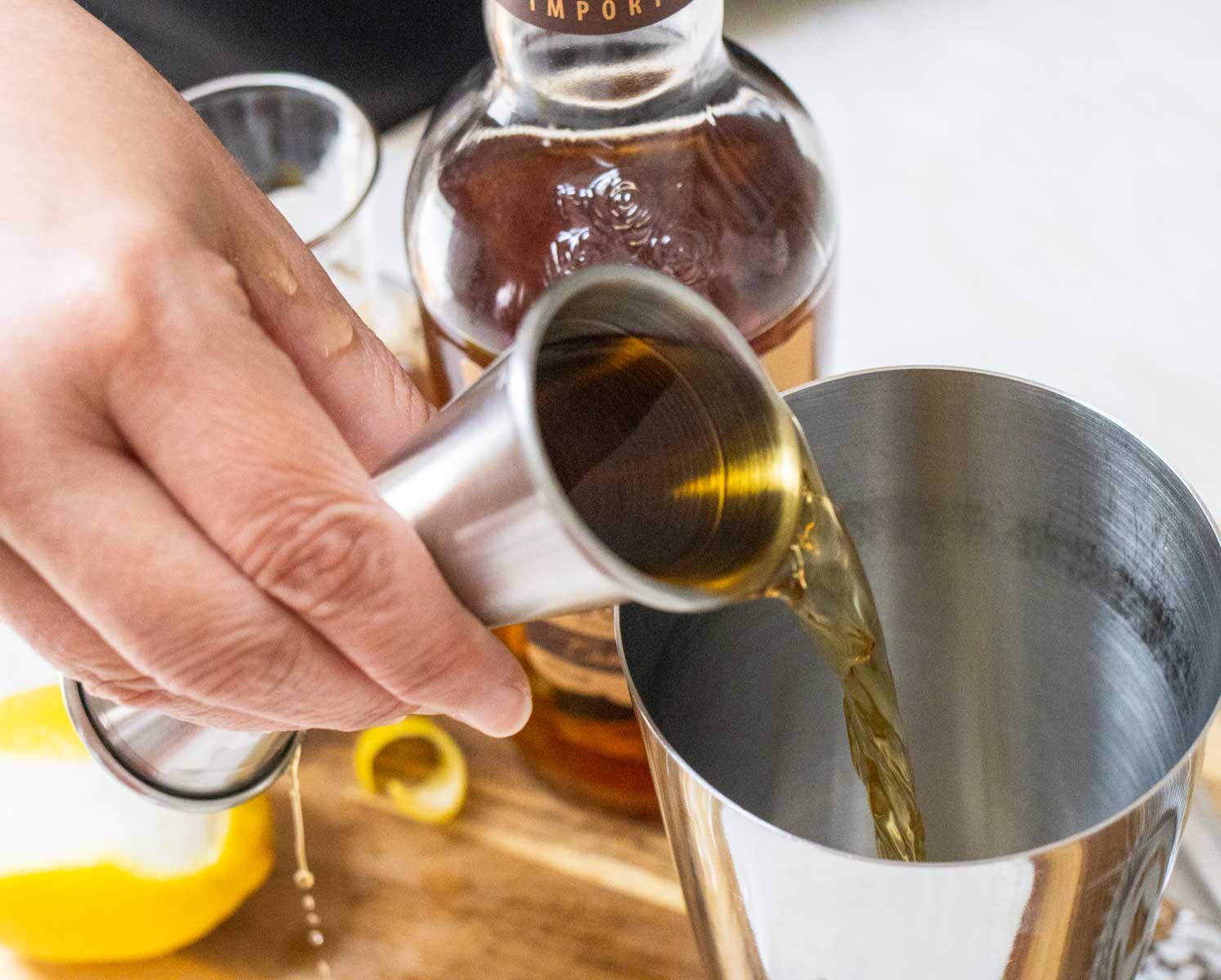 Pouring Bourbon into a Gold Rush Cocktail