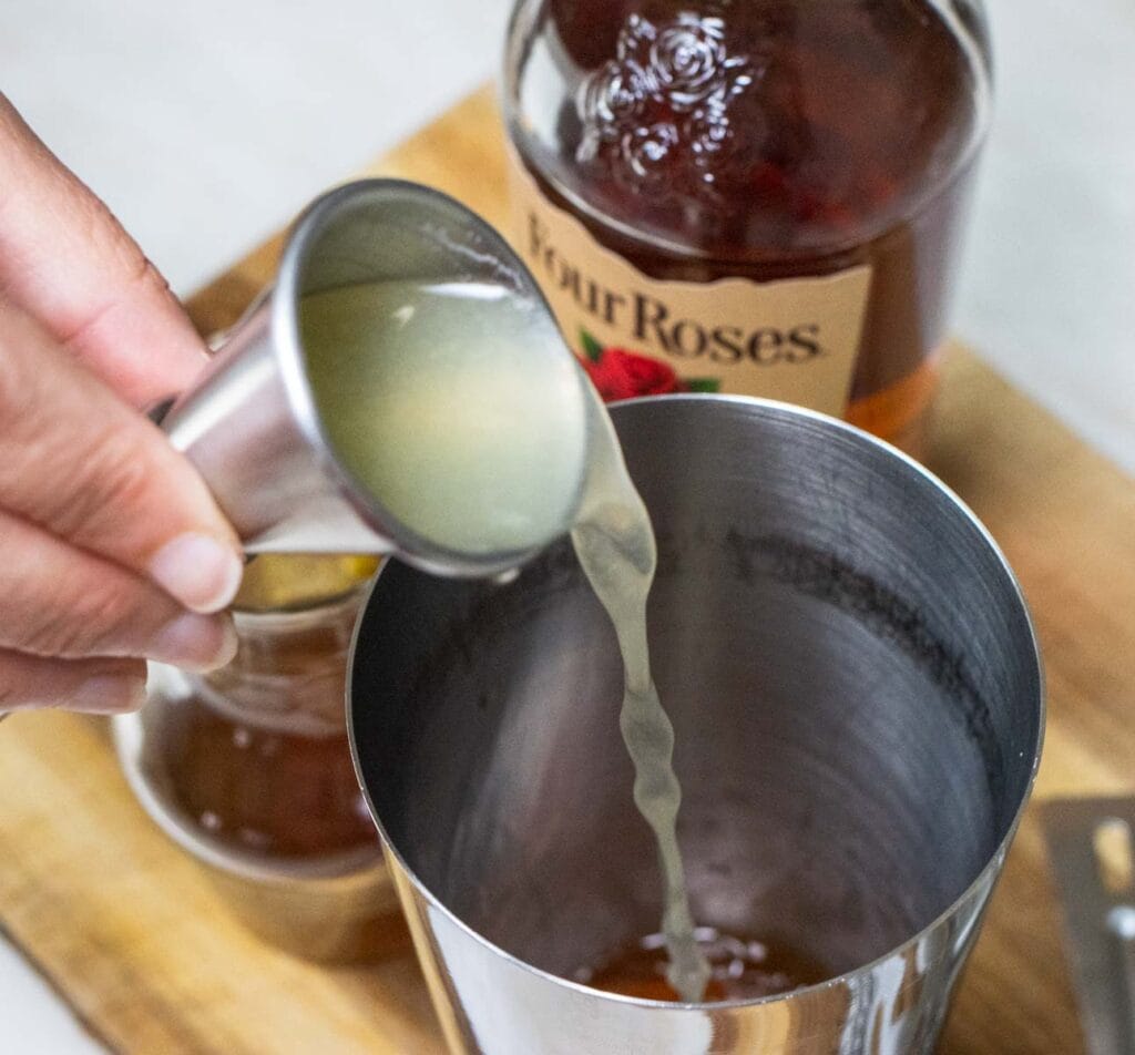 Pouring Lemon Juice into a Gold Rush Cocktail