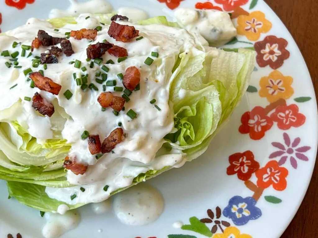 Close up view of a wedge salad on a flower rimmed plate