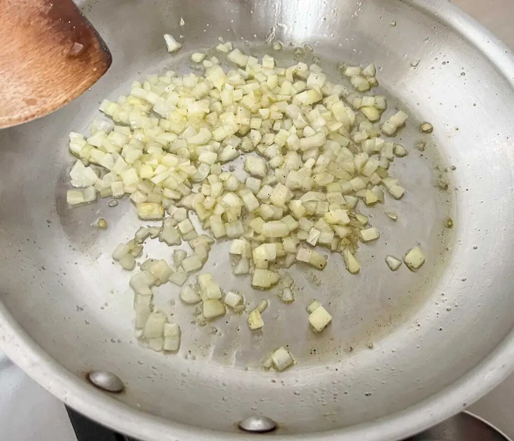 Diced Onions sauteeing in a stainless steel pan