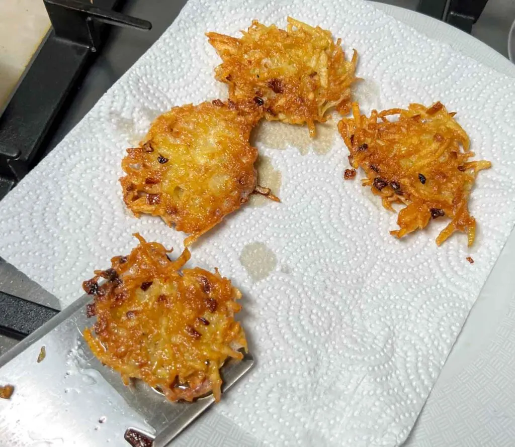 Moving finished potato latkes to a paper towel for draining