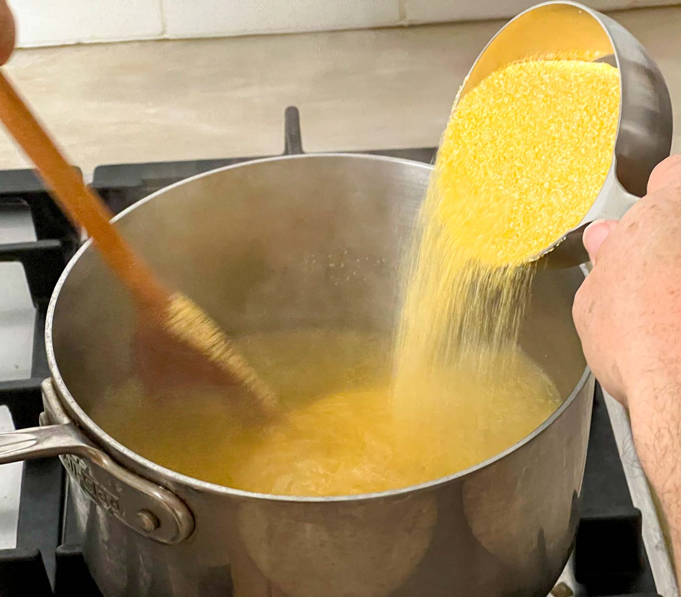 Polenta being added in a thin stream to boiling water