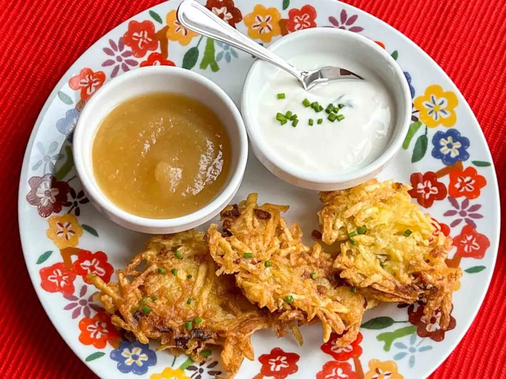 Potato Latkes on a multicolored plate with sour cream and applesauce