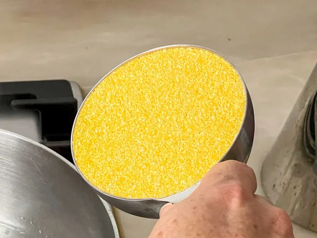 Raw polenta in a one cup measuring cup