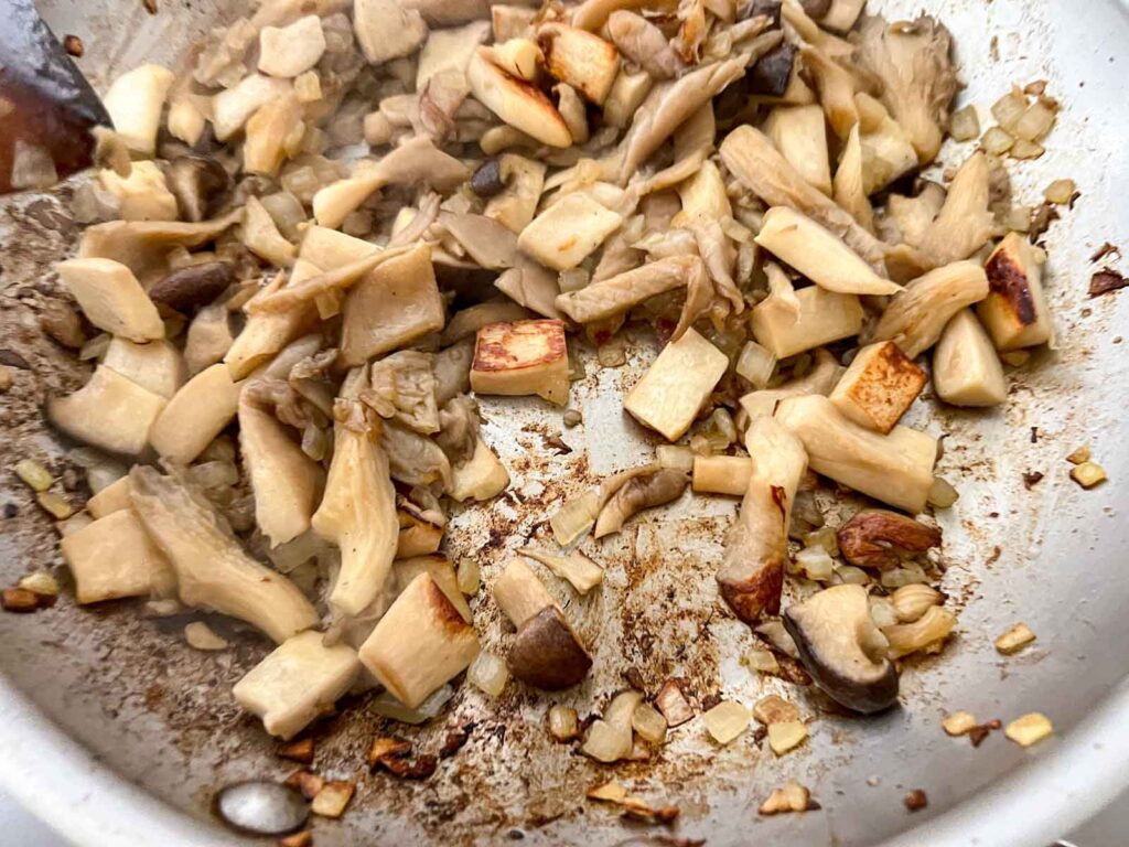Sauteed mushrooms forming a brown fond in a stainless steel pan