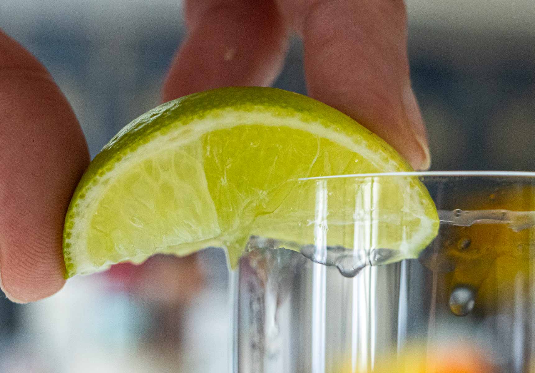 Squeezing Lime Wedge on Highball Glass