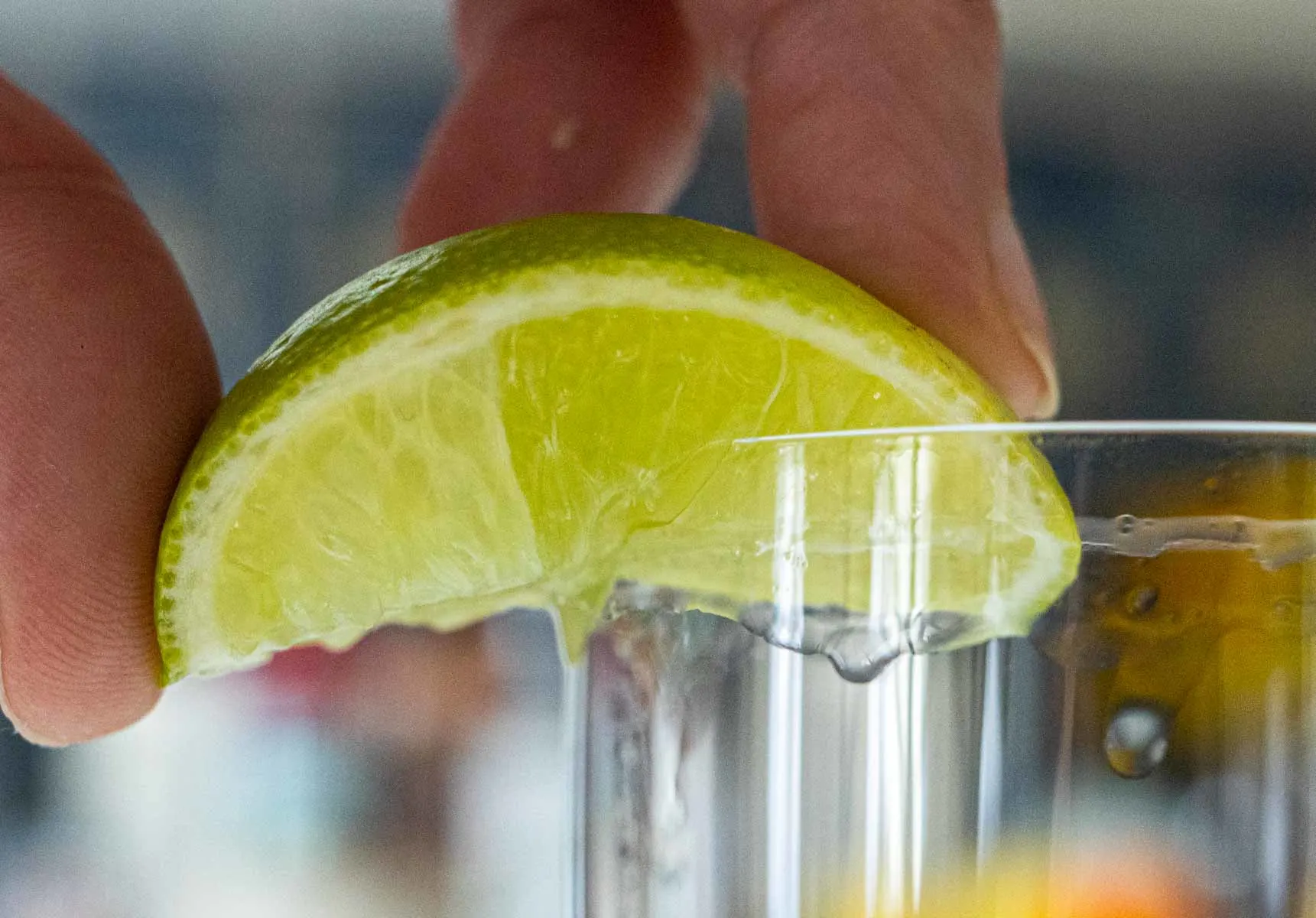 Squeezing Lime Wedge on Highball Glass