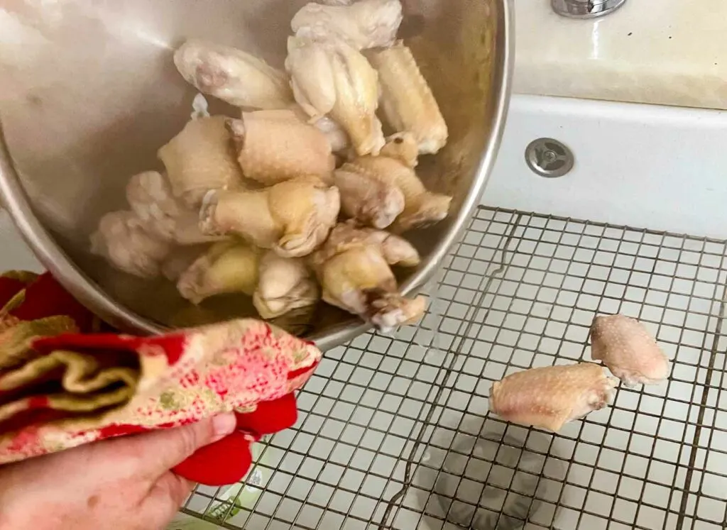 Draining blanched chicken wings in the sink on a wire rack