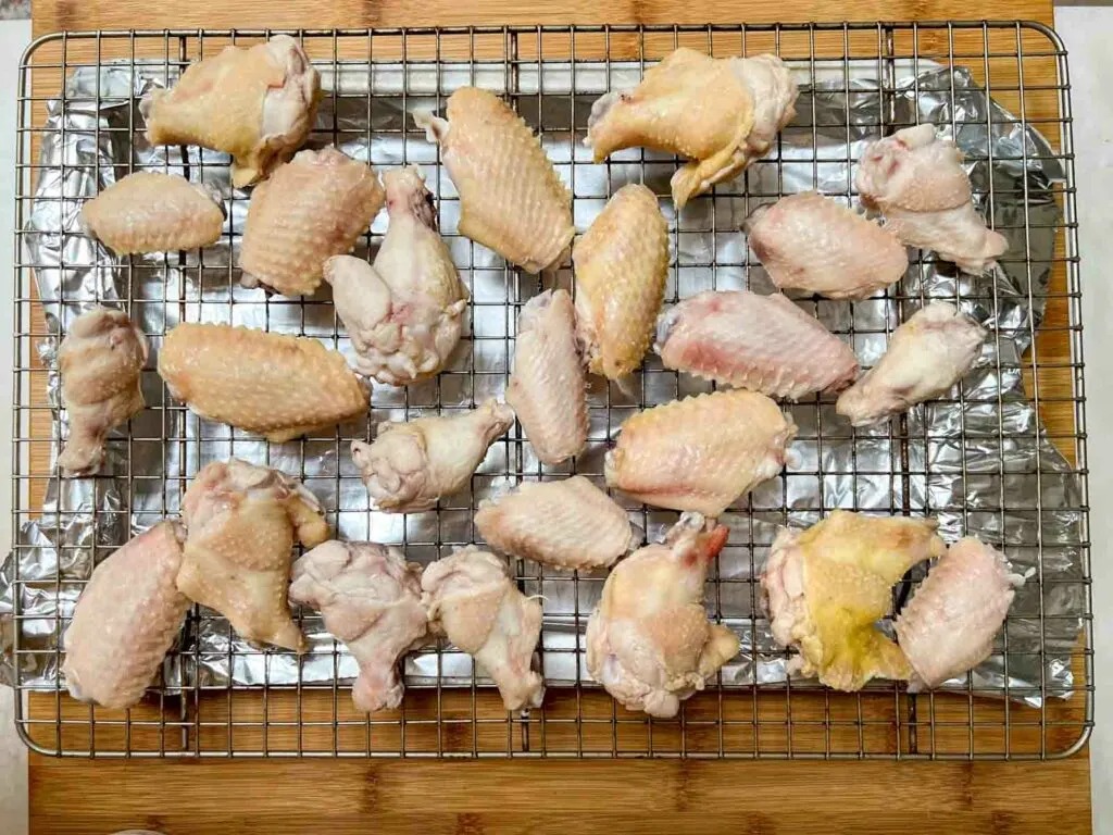 Wings ready to be baked on a wire rack over a sheet pan