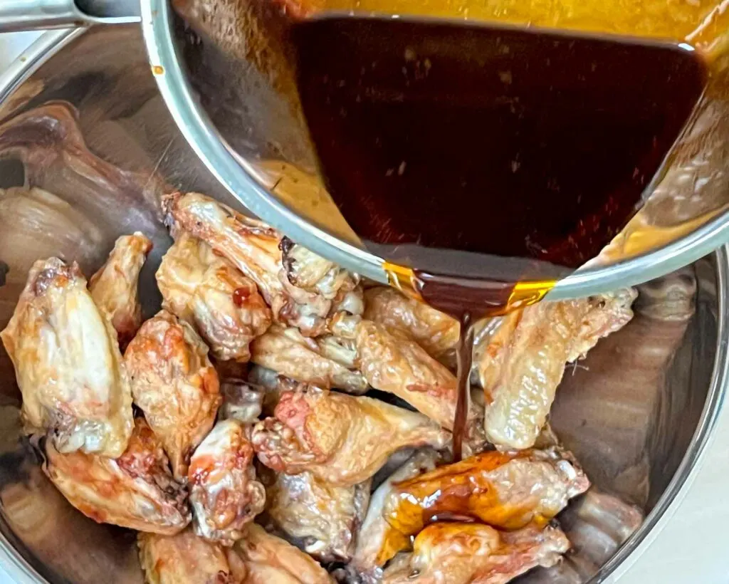 Pouring Asian Sauce over Browned Chicken Wings