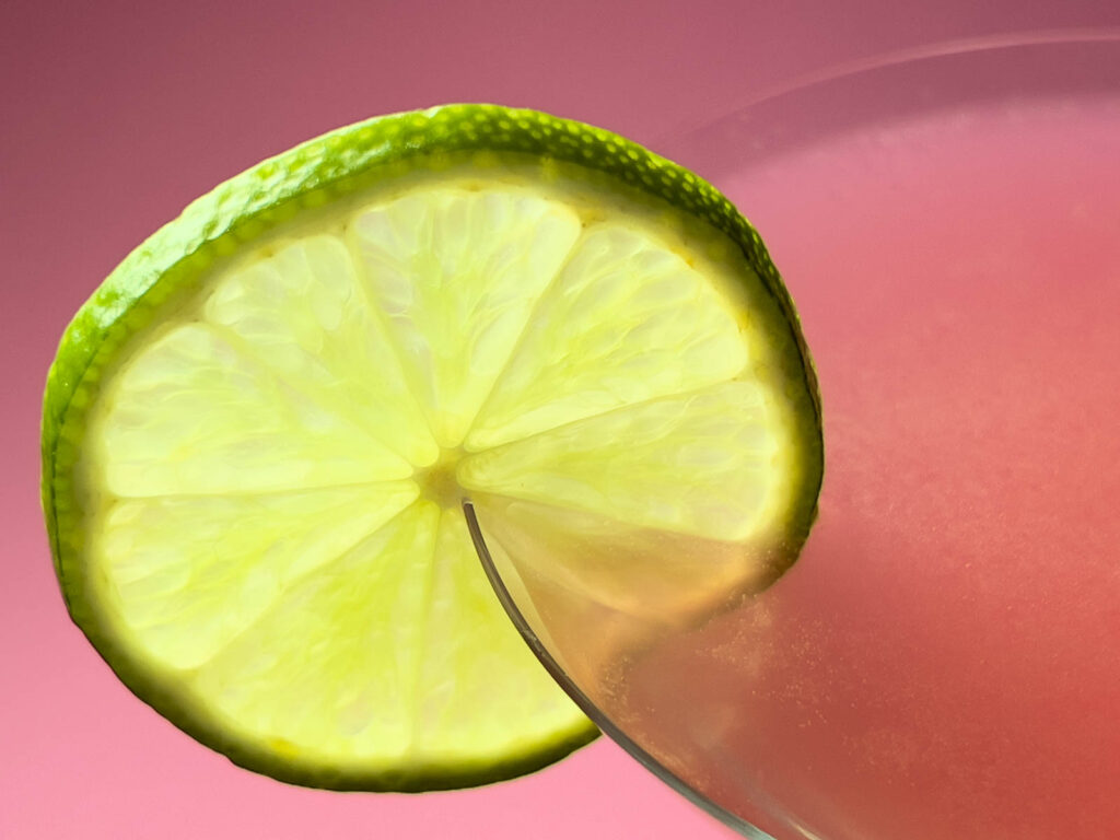 Cosmopolitan Cocktail with Lime Wheel and Pink Background