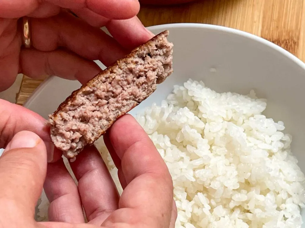 Holding a cut hamvurger over rice