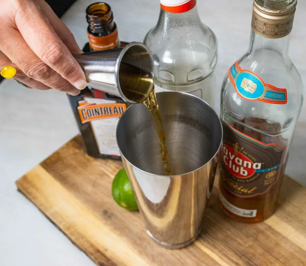 Pour rum into a Mai Tai cocktail