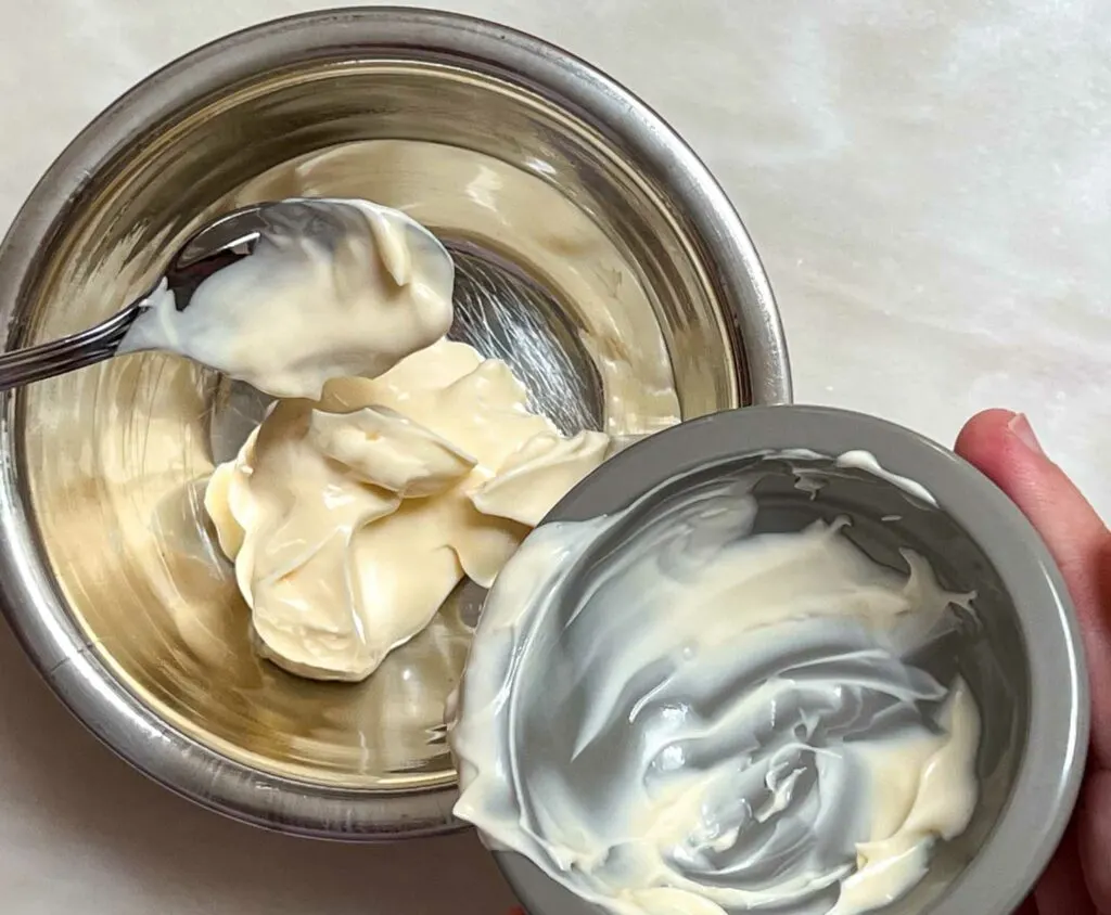 Pouring Mayonnaise into a silver mixing bowl
