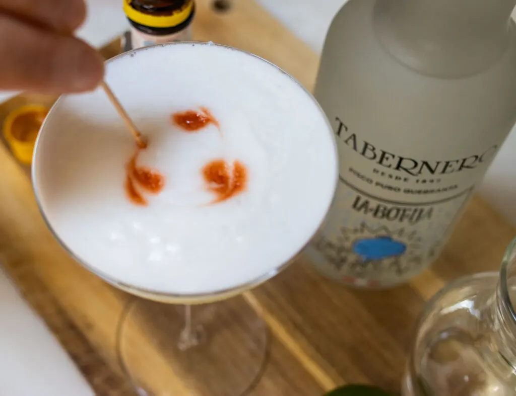 Swirling Angostura Bitters on a Pisco Sour