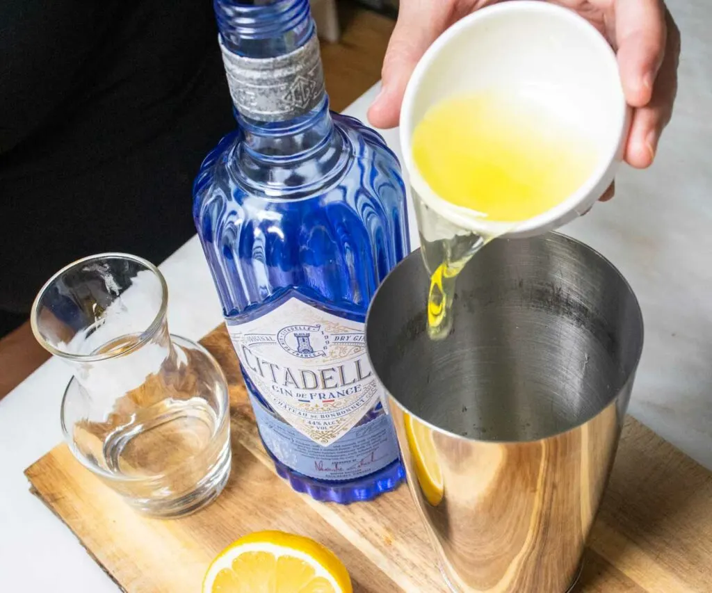 Pouring Egg White into Gin Sour Cocktail