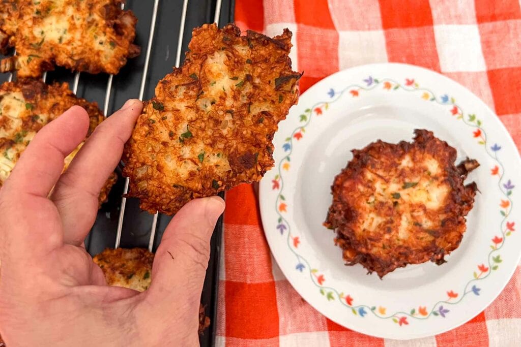 Salt cod passover latke being placed on a plate by hand