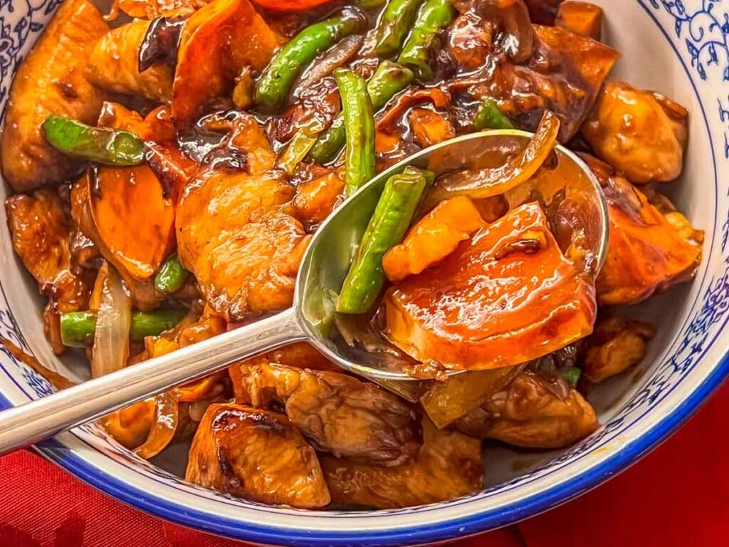 Chicken and persimmons in a bowl with a serving spoon