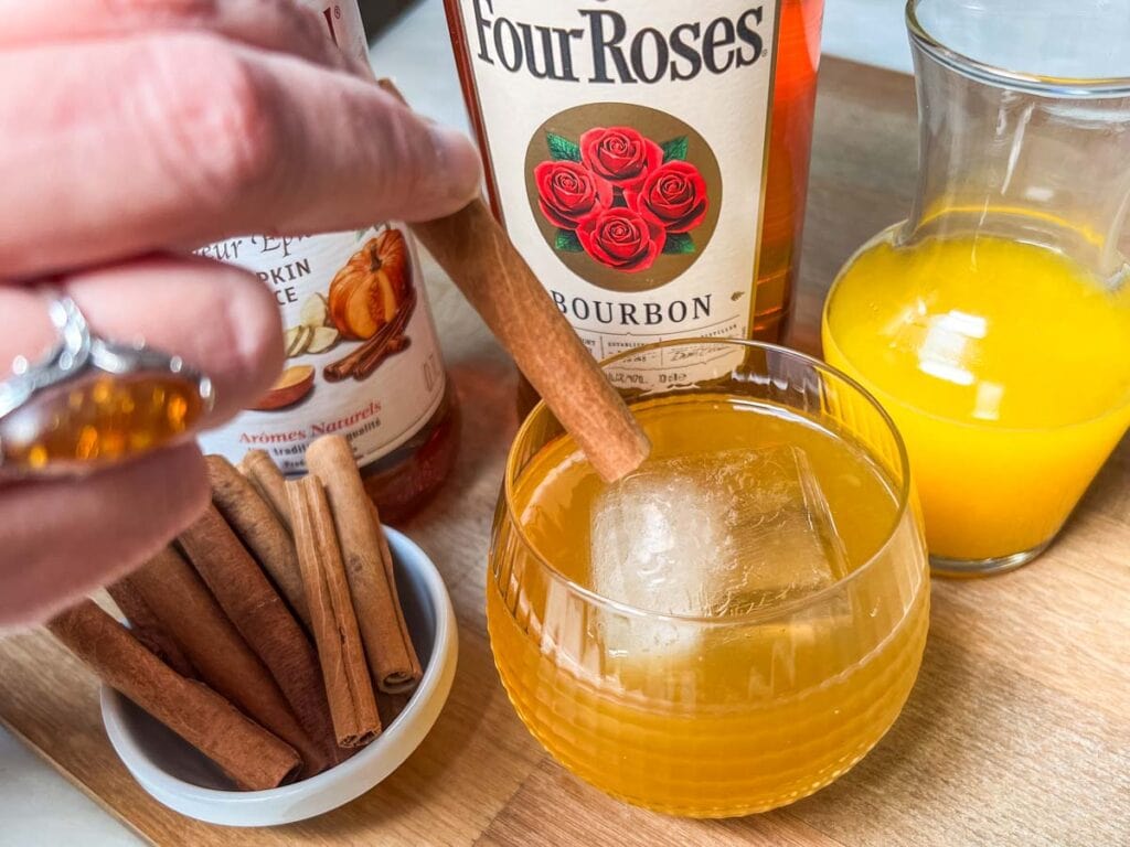 Garnishing a Pumpkin Bourbon Smash with a Cinnamon Stick